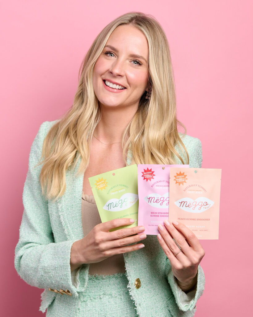 Smiling Meggo Sweets Founder holding packages of Gummie Smoochies